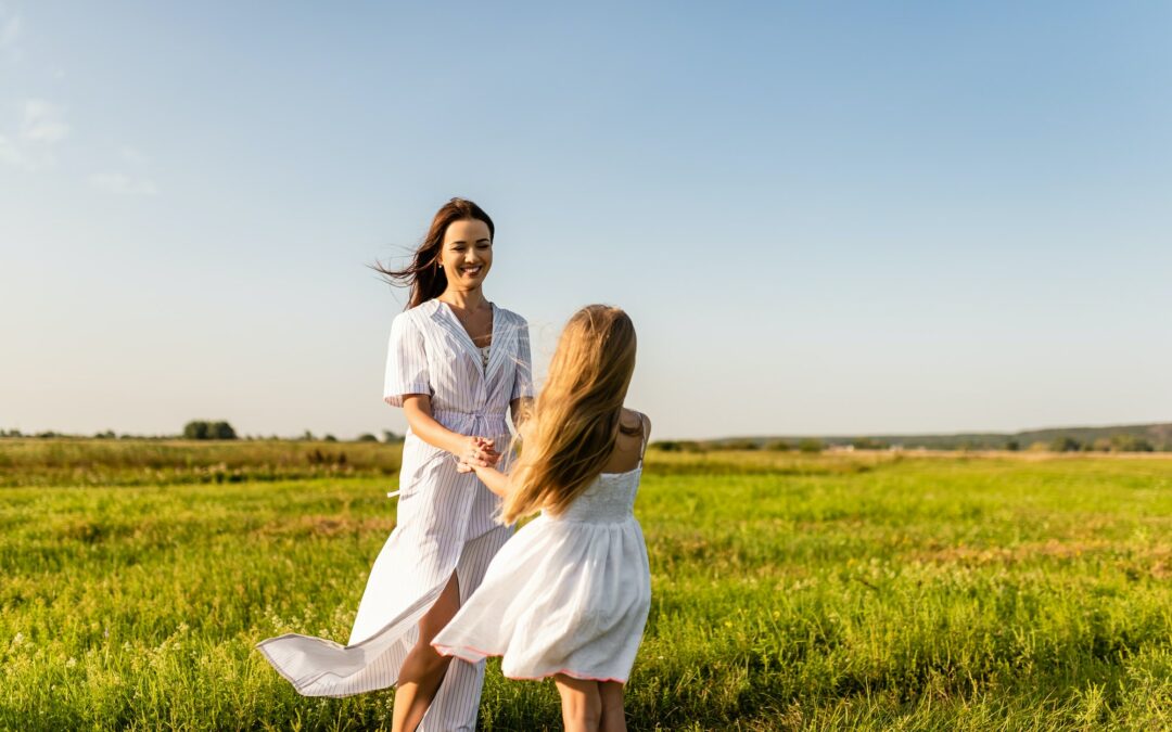 beautiful happy mother and daughter playing in green meadow